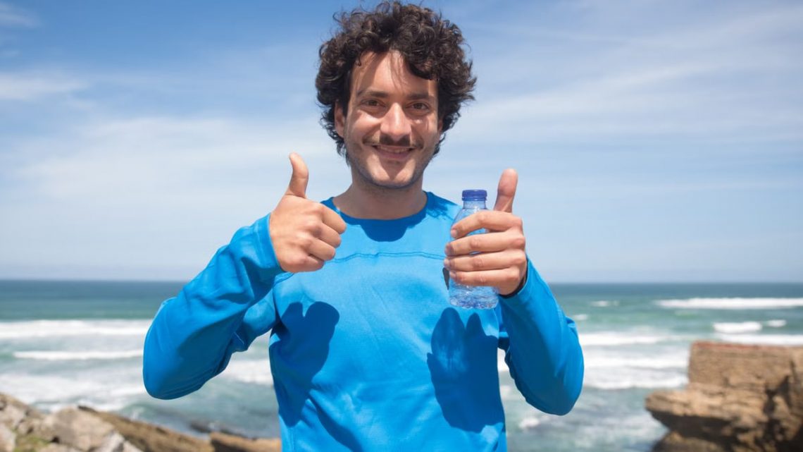 Smiling man enjoying a sunny day at the beach in Portugal, giving thumbs up.